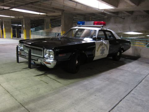 1991 Ford LTD Crown Victoria - black-and-white Dodge Highway Patrol sedan with a star emblem, push bumper and roof lights, parked in a garage.