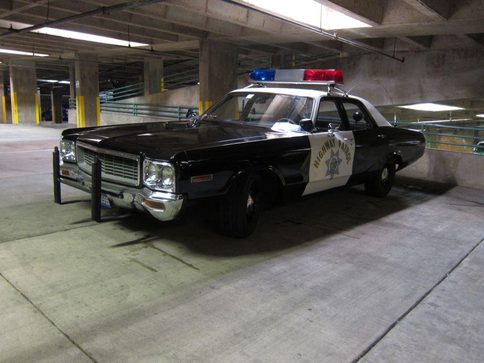 Black-and-white Dodge Highway Patrol car with push bumper in garage