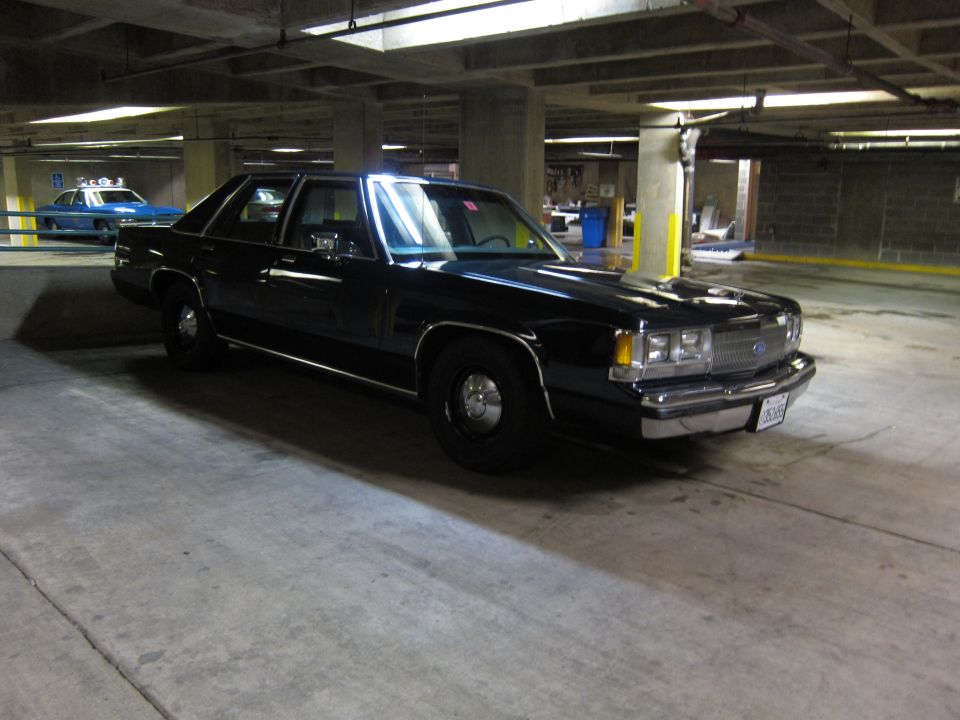 Black Ford LTD Crown Victoria police sedan parked in concrete garage