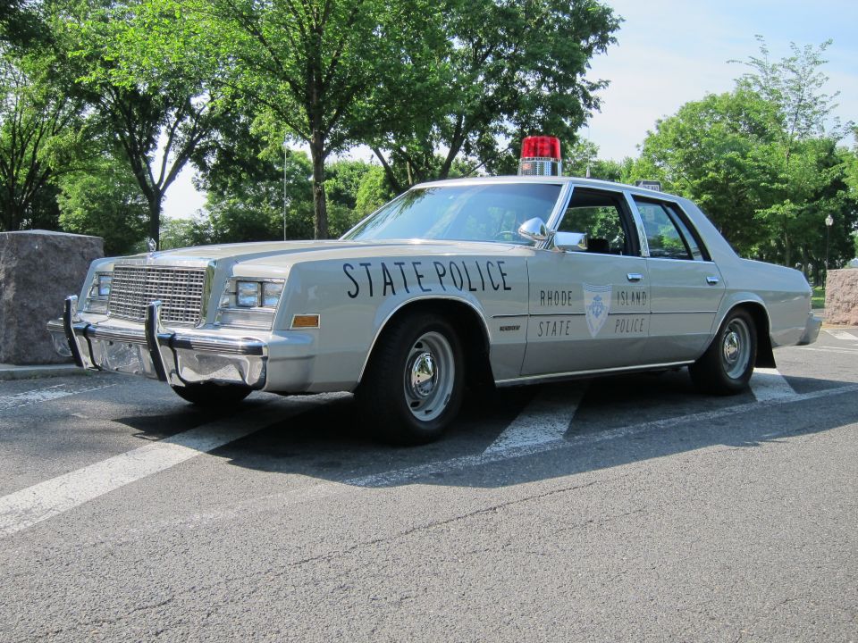 Silver Rhode Island State Police sedan with red beacon, front three-quarter