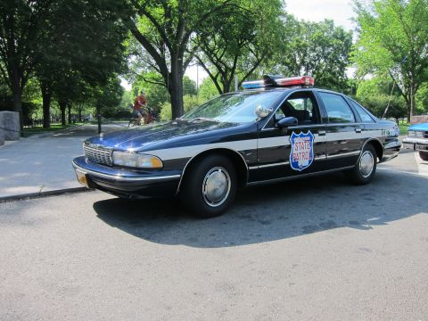 1991 Ford LTD Crown Victoria - dark blue Chevrolet Caprice 'State Patrol' sedan with a shield emblem and roof lights, parked on a street.