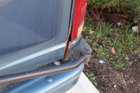 1980 Ford Bronco - The rear corner of a blue SUV shows significant rust damage around the taillight assembly.