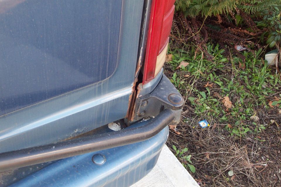 Blue SUV rear corner with visible rust around the taillight and bumper
