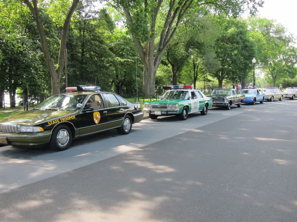 Row of vintage police cars led by black State Trooper Chevrolet Caprice sedan
