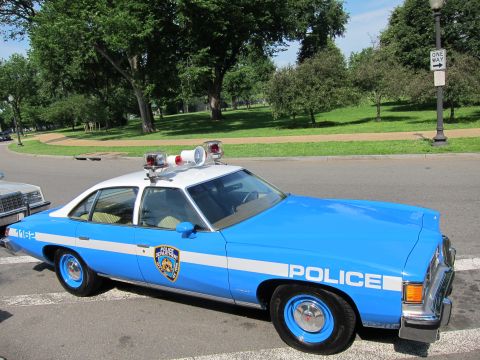 1991 Ford LTD Crown Victoria - vintage blue-and-white NYPD police sedan marked POLICE 1162 sits on a park road under leafy trees.