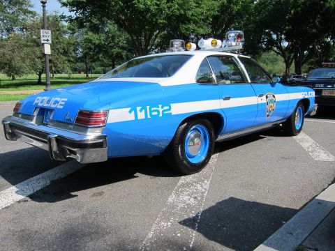 1991 Ford LTD Crown Victoria - Rear view of a blue-and-white NYPD police sedan marked POLICE 1162 with roof lights, parked in a lot.