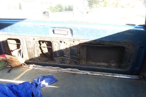 1980 Ford Bronco - Interior view of a vehicle's rear panel with open storage compartments. A blue tarp and bag are visible on the floor.