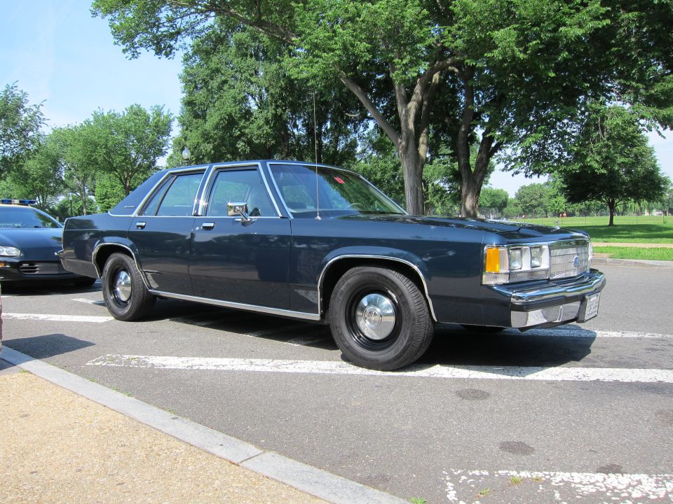 Dark blue four-door sedan parked in a sunlit lot near trees