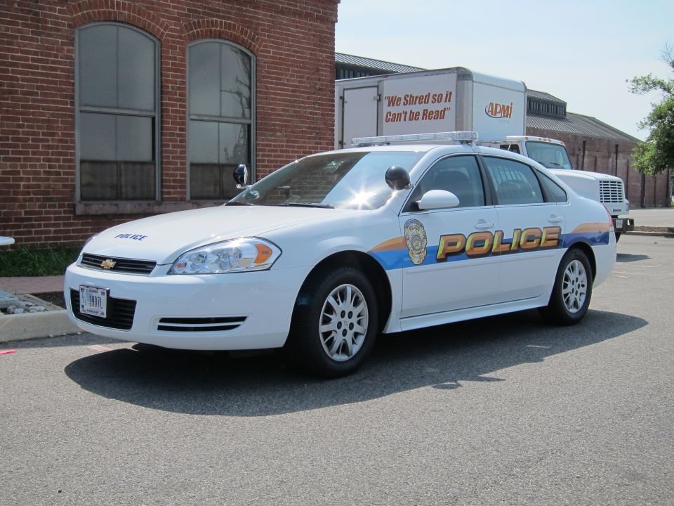 Front-quarter view of white Chevrolet Police sedan by brick building
