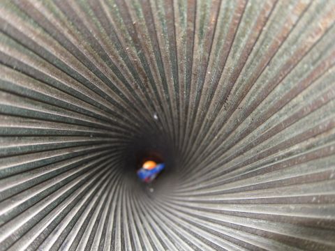 1991 Ford LTD Crown Victoria - Extreme macro shot looking down the spiraling ridged interior of a metal tube toward a tiny bright opening.
