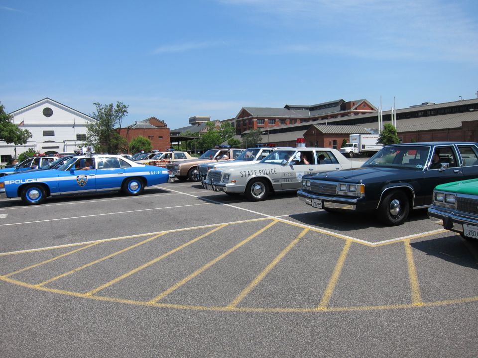 Row of classic police sedans including a blue NYPD car and State Police unit