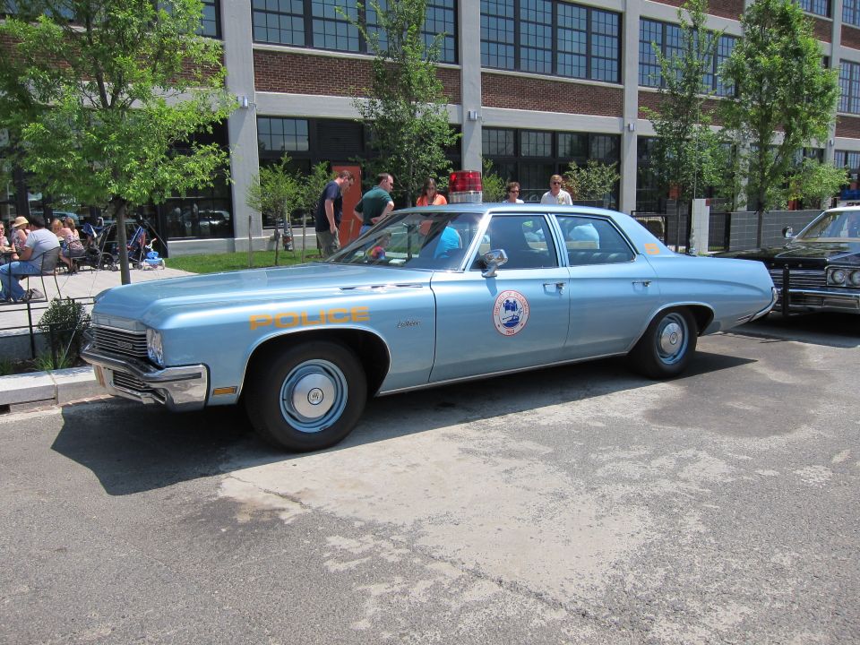 Light blue vintage police sedan with roundel emblem parked outside loft building
