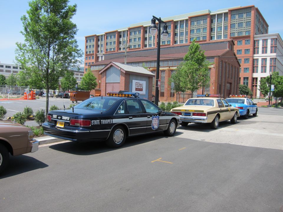Dark blue State Trooper sedan parked with other police cars in a lot