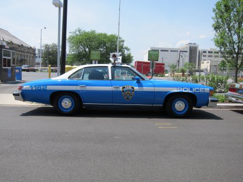 1991 Ford LTD Crown Victoria - two-tone blue-and-white NYPD police sedan numbered 1162 with blue wheels sits at a three-quarter front angle on a street.
