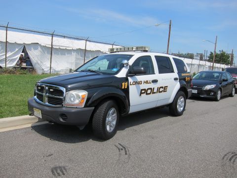1991 Ford LTD Crown Victoria - black-and-white Dodge Durango marked Long Hill Police unit 11 parked near a fenced lot.