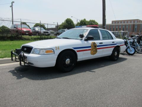 1991 Ford LTD Crown Victoria - white Ford Crown Victoria patrol sedan unit 34 with red-white-blue stripes and a gold badge decal.