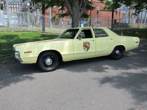 1991 Ford LTD Crown Victoria - pale yellow vintage police sedan with a Maryland shield door decal and single roof beacon.