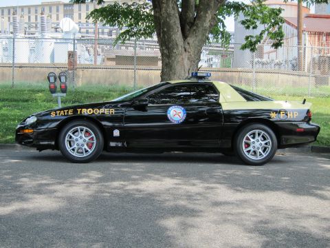 1991 Ford LTD Crown Victoria - Side view of a black-and-tan Chevrolet Camaro coupe lettered State Trooper FHP with a round seal.