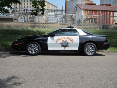 1991 Ford LTD Crown Victoria - black-and-white Chevrolet Camaro coupe lettered Highway Patrol with a gold star shield on the door.