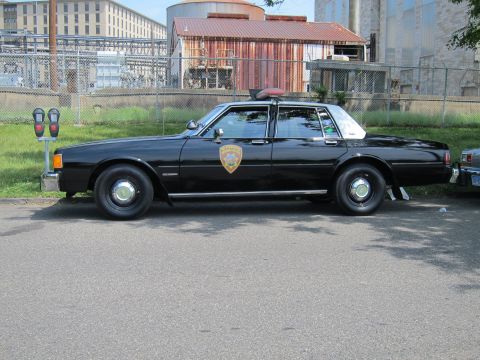 1991 Ford LTD Crown Victoria - Side view of a black boxy Chevrolet Caprice police sedan with a round door seal and roof lights.