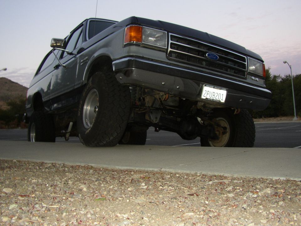 Low-angle front view of lifted dark gray Ford 4x4 truck with chrome grille and off-road tires