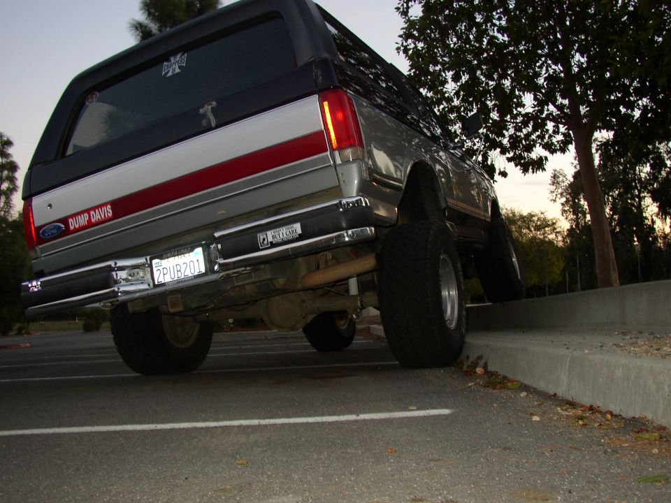 Low rear view of lifted gray and red Ford SUV with California plate 2PUB201 on off-road tires.
