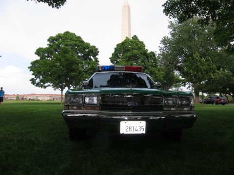 1991 Ford LTD Crown Victoria - green and white Ford full-size sedan with a roof light bar sits on a lawn with the Washington Monument and trees in the background.