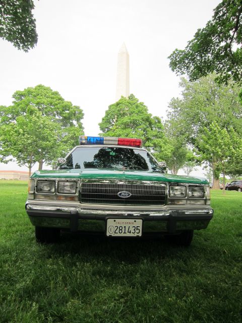 1991 Ford LTD Crown Victoria - green and white Ford full-size sedan with a roof beacon bar and California plate is photographed head-on with the Washington Monument behin…
