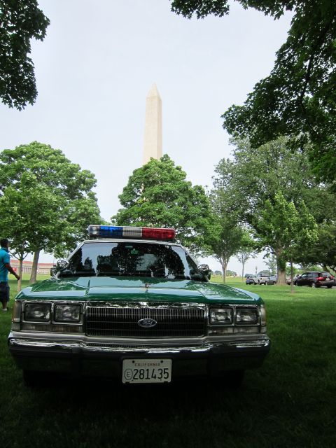 1991 Ford LTD Crown Victoria - green and white Ford full-size sedan with a roof light bar sits on grass framed by trees and the Washington Monument.