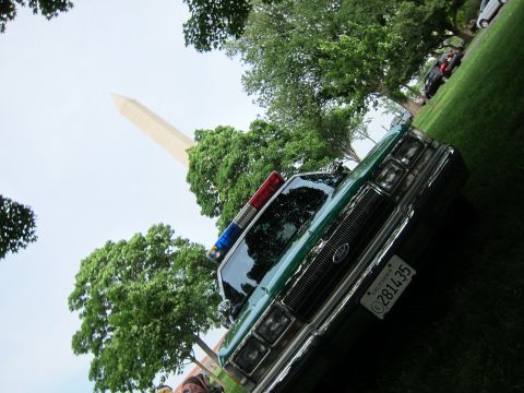 1991 Ford LTD Crown Victoria - green and white Ford full-size sedan with a roof beacon bar is shot at a dramatic tilted angle with the Washington Monument behind.
