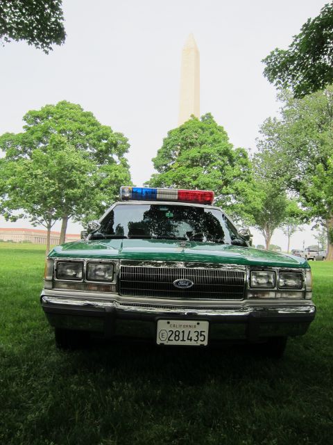 1991 Ford LTD Crown Victoria - green and white Ford full-size sedan with a roof light bar and California plate sits head-on with the Washington Monument behind it.