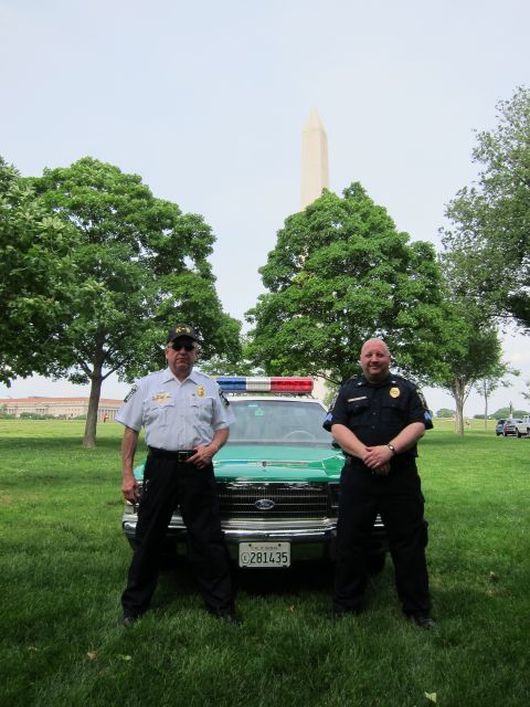 1991 Ford LTD Crown Victoria - Two officers stand beside a green-and-white police sedan bearing plate 281435, with the Washington Monument behind on a grassy lawn.