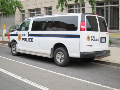 1991 Ford LTD Crown Victoria - Rear three-quarter view of a white FBI Police van showing dual side and rear markings parked curbside.