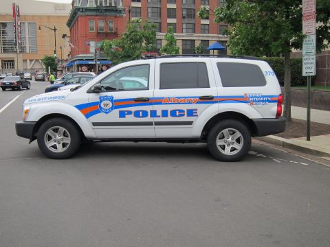 1991 Ford LTD Crown Victoria - white Albany Police Dodge Durango with blue and orange striping parked on a downtown street.
