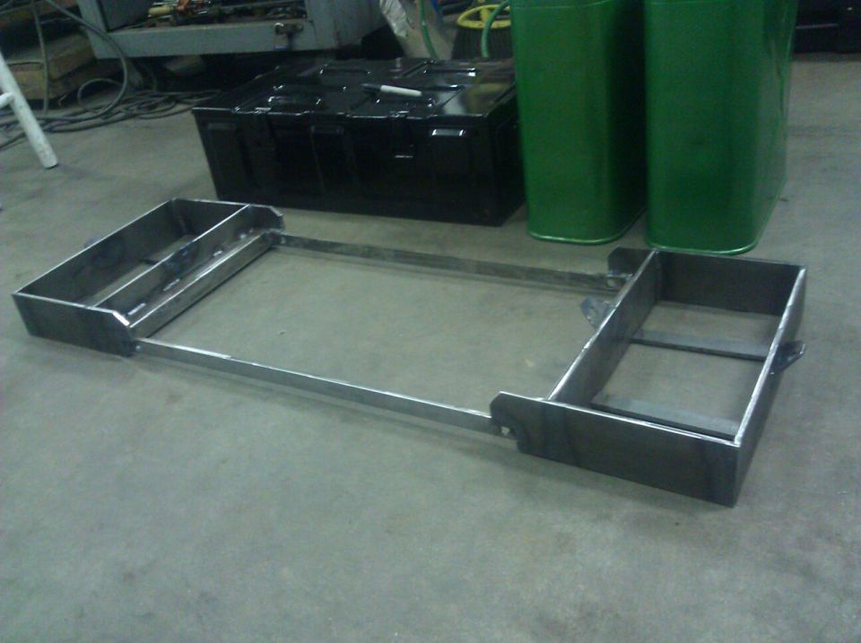 Custom metal frame with two rectangular boxes on either side, resting on a concrete floor