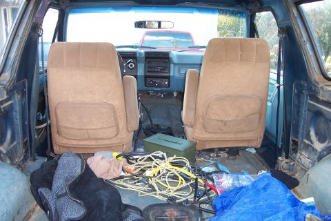 1980 Ford Bronco - Looking from the rear cargo area into the interior of a 1980 Ford Bronco, with a red vehicle visible through the windshield.