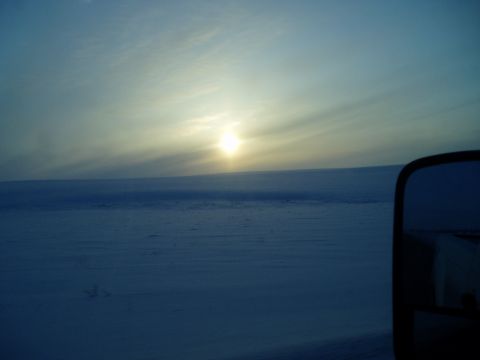 2009 Kenworth T800 - A truck's side mirror shows a reflection of a desolate, snow-covered landscape at sunrise.