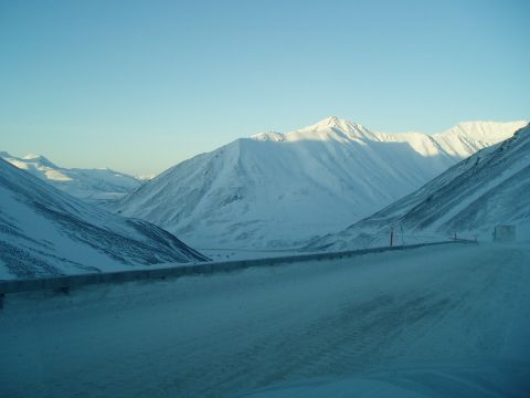 2009 Kenworth T800 - A truck travels through a snow-covered mountain pass under a clear blue sky.