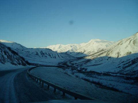 2009 Kenworth T800 - A road winds through a snow-covered mountain valley on a clear day.