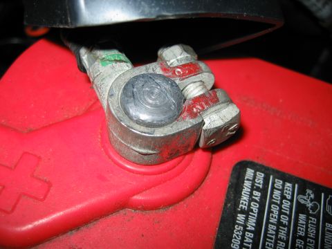 1992 Ford Bronco - Close-up of a battery terminal connection on a red battery, with some text visible on the casing.