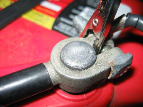 1992 Ford Bronco - Jumper cable clamp connected to a car battery terminal.