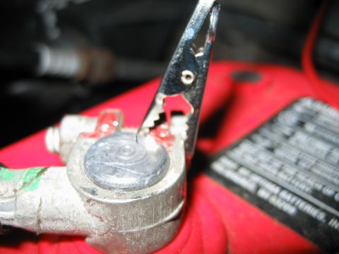 1992 Ford Bronco - A close-up view shows a metal clamp connected to a vehicle battery terminal.