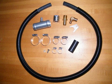 2004 Ford Crown Victoria - A collection of automotive parts, including flexible tubing and various metal connectors and clamps, laid out on a wooden surface.