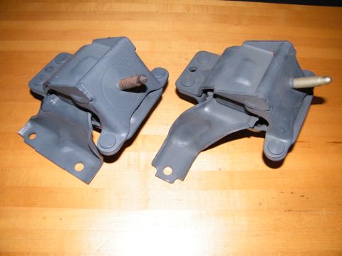 2004 Ford Crown Victoria - Two engine mounts are shown, each with a metal bracket and a threaded bolt protruding from the rubber component.