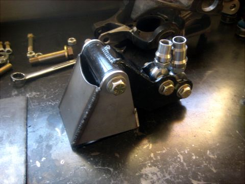 1996 Ford Bronco - Close-up of a custom steering component, likely for off-road use, a fabricated metal bracket and hydraulic fittings.