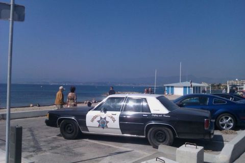 1991 Ford LTD Crown Victoria - A 1991 Ford Crown Victoria police car is parked near the beach with other vehicles.
