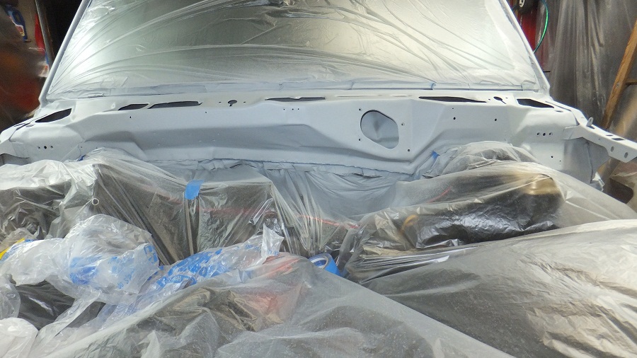 Engine bay covered in plastic sheeting for painting. Parts of the engine are visible under the plastic