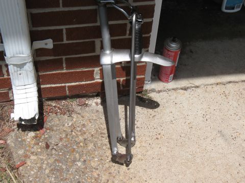 1994 Ford Bronco - A metal clamp sits on concrete near a brick wall and a downspout, with a spray can nearby.