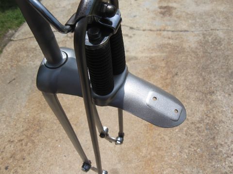 1994 Ford Bronco - Close-up of a motorcycle's front suspension system, silver-painted components and black protective bellows.