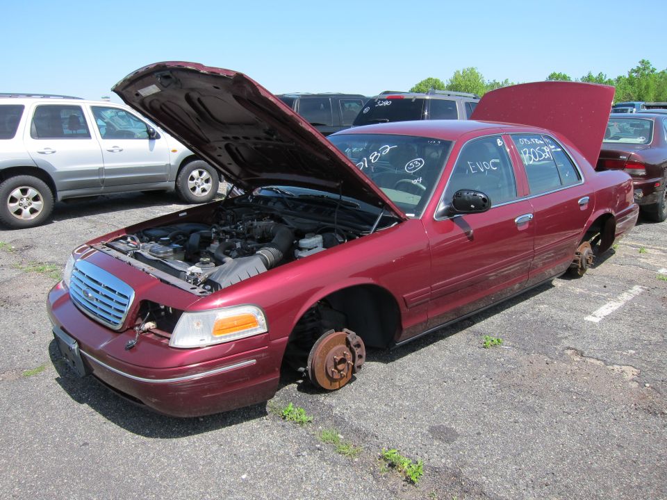 Red 2001 Ford Crown Victoria with hood open, missing wheels